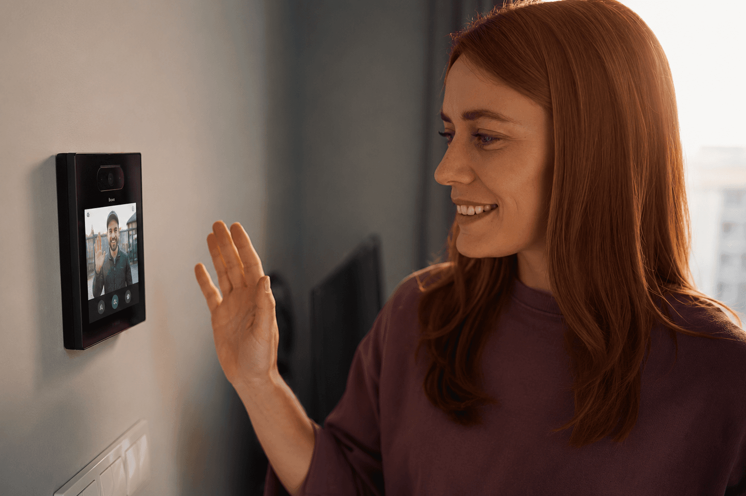 Wall-mounted video intercom screen showing a visitor on a call
